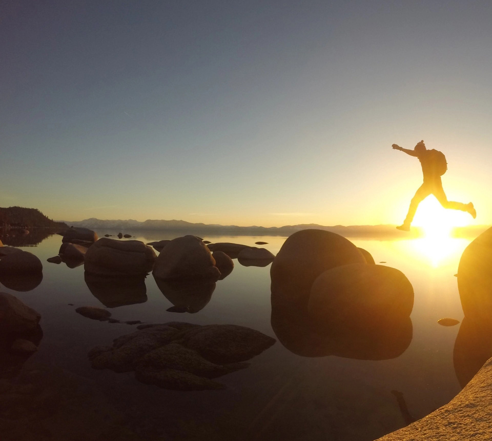 Jumping across large boulders at sunset